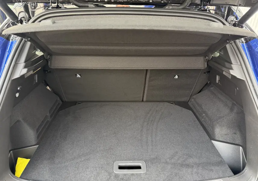 Coffre ouvert du Renault Austral 2025 bleu Iron avec intérieur noir et cache-bagages déployé, vue arrière.