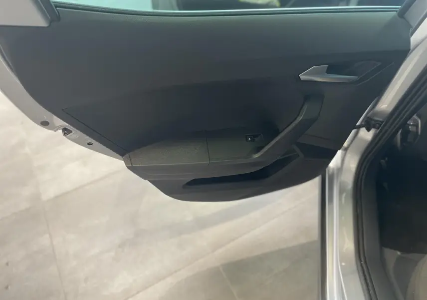 Vue rapprochée de la porte avant gauche noire du SEAT ARONA 2024, avec poignée argentée et bouton de lève-vitre.