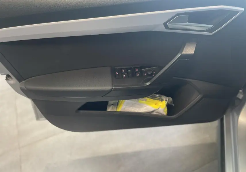 Porte côté gauche du SEAT Arona 2024, avec commandes de vitres électriques et rangement inférieur noir.