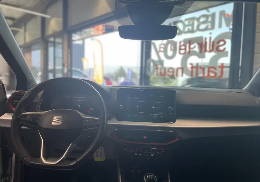 Vue intérieure avant du tableau de bord de la SEAT Arona 2024 avec volant sport cuir et écran tactile 8,25 pouces.