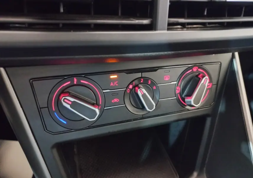 Gros plan sur les commandes de climatisation avec éclairage rouge à l'intérieur d'une Volkswagen Polo noire de 2020.