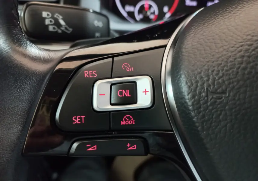 Gros plan sur les commandes du régulateur de vitesse du volant cuir noir d'une Volkswagen Polo 2020.