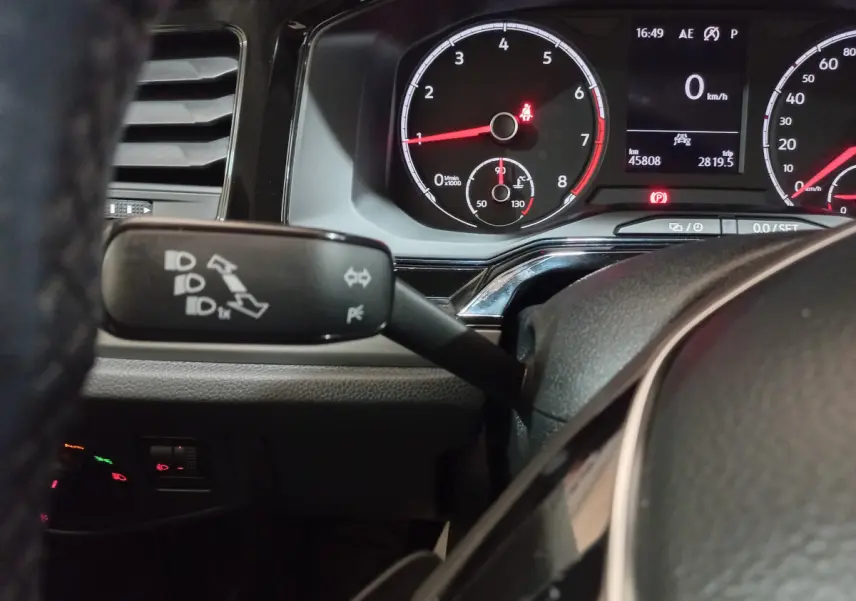 Gros plan sur le tableau de bord et le commodo gauche de la Volkswagen Polo noire, affichage digital et compte-tours visibles.