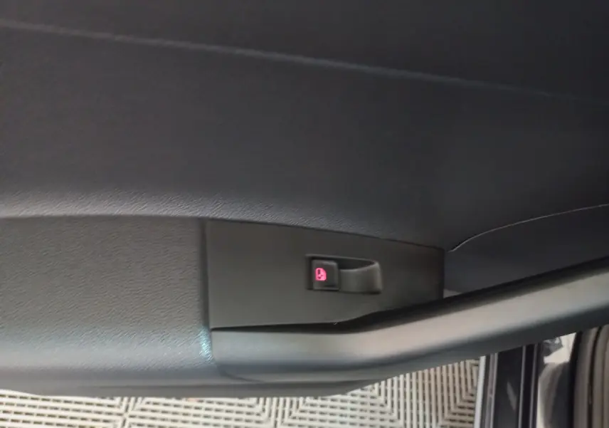 Bouton de verrouillage des portes rouge sur la garniture intérieure noire de la porte avant droite d'une Volkswagen Polo noire.