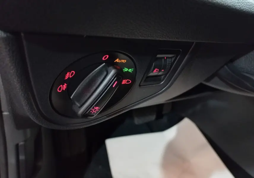 Gros plan sur le bouton de commande des phares avec réglage automatique dans l'habitacle noir du Volkswagen Polo 2020.