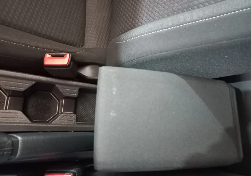 Gros plan sur l'accoudoir central et les sièges noirs en tissu de la Volkswagen Polo 2020 côté conducteur.