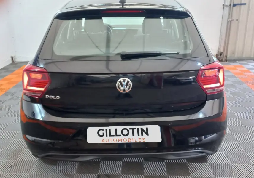 Vue arrière d'une Volkswagen Polo noire de 2020 avec feux arrière allumés dans un garage.