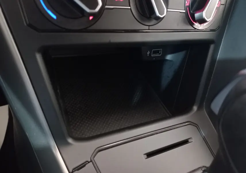 Gros plan sur la console centrale noire de la Volkswagen Polo 2020, montrant les commandes de climatisation et une prise USB.