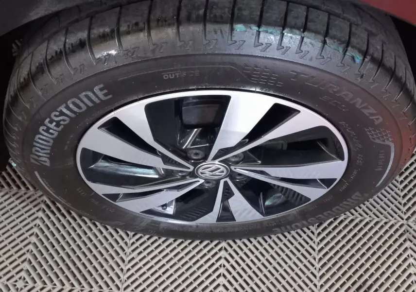 Gros plan sur la roue avant gauche d'une Volkswagen Polo noire avec jante alliage bicolore et pneu Bridgestone Turanza.