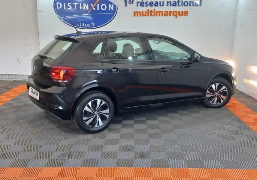 Volkswagen Polo noire vue de profil côté gauche dans un showroom avec jantes alliage et feux arrière allumés.