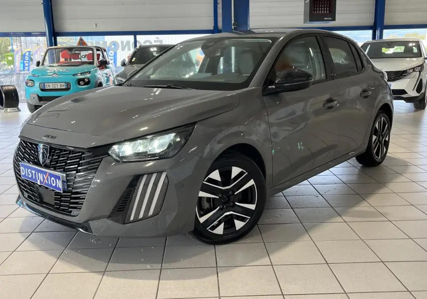 Peugeot 208 gris clair sélénium vue 3/4 avant avec calandre noire et jantes alliage bi-tons en showroom.