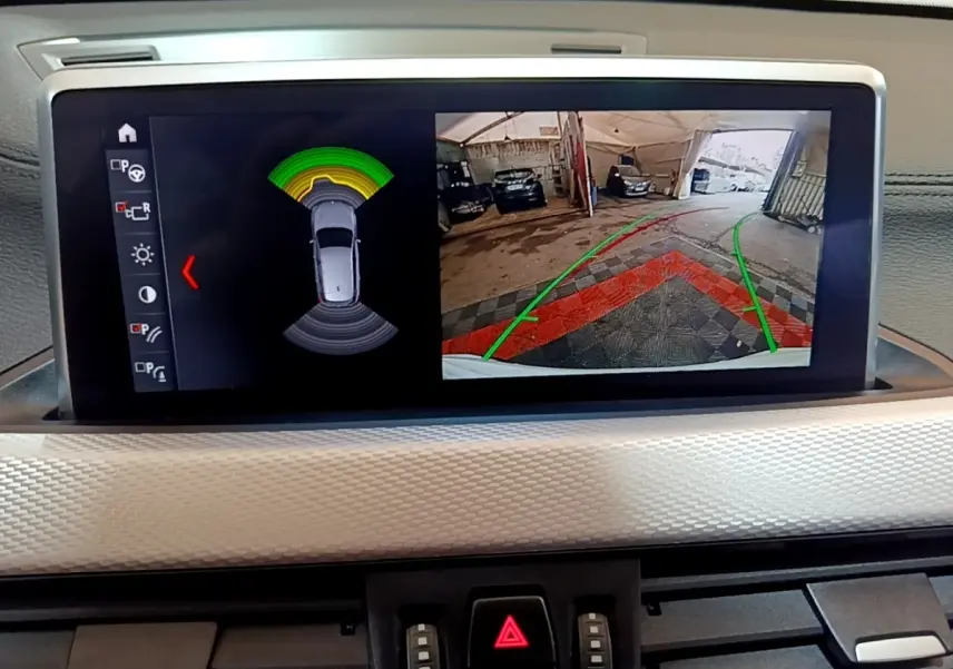 Écran tactile intérieur montrant la caméra de recul et les capteurs de stationnement du BMW X1 blanc 2022.