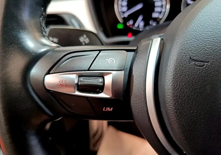 Gros plan sur les commandes du régulateur de vitesse au volant cuir noir du BMW X1 blanc sDrive18i M Sport 2022.