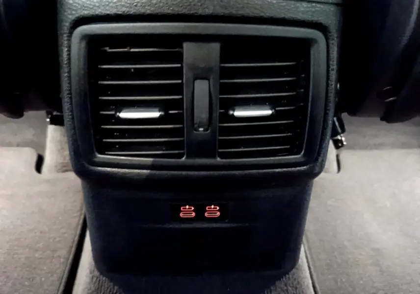 Gros plan sur la sortie d’air arrière noire et les commandes de chauffage des sièges du BMW X1 blanc sDrive18i M Sport 2022.