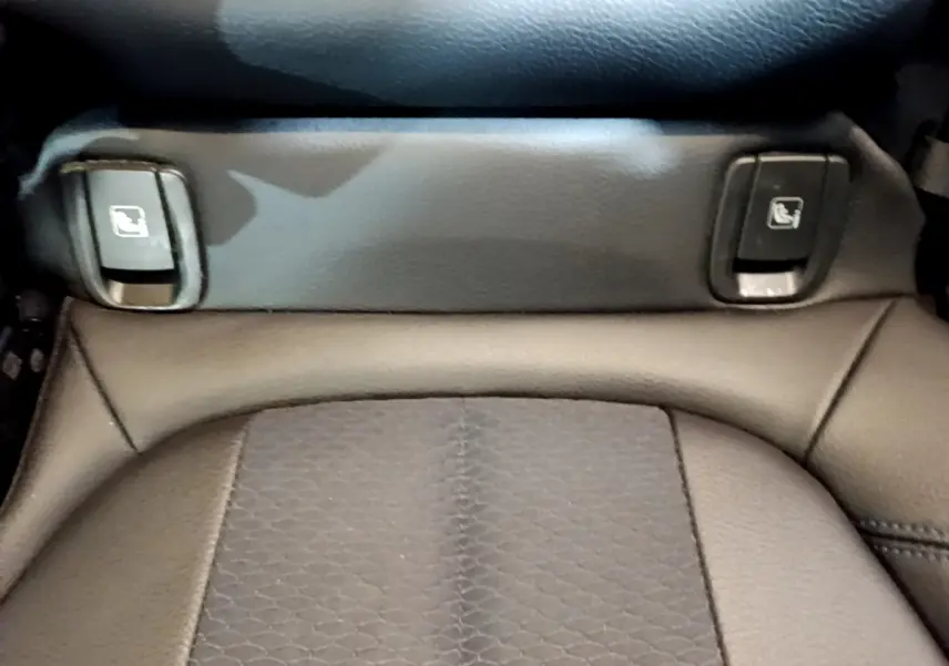 Gros plan sur les commandes de rabattement des sièges arrière en cuir noir dans un BMW X1 blanc.