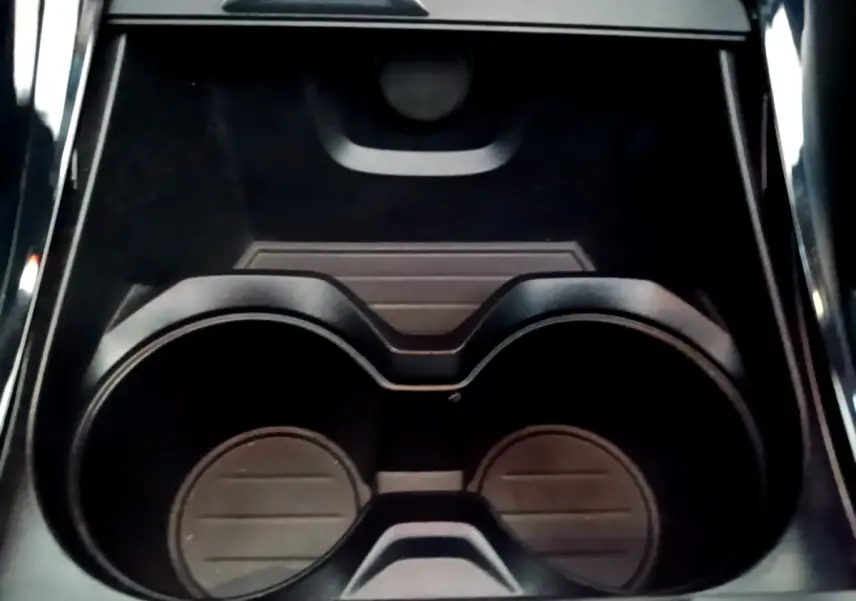 Gros plan sur les porte-gobelets noirs au centre de la console intérieure d’une BMW X1 blanche.