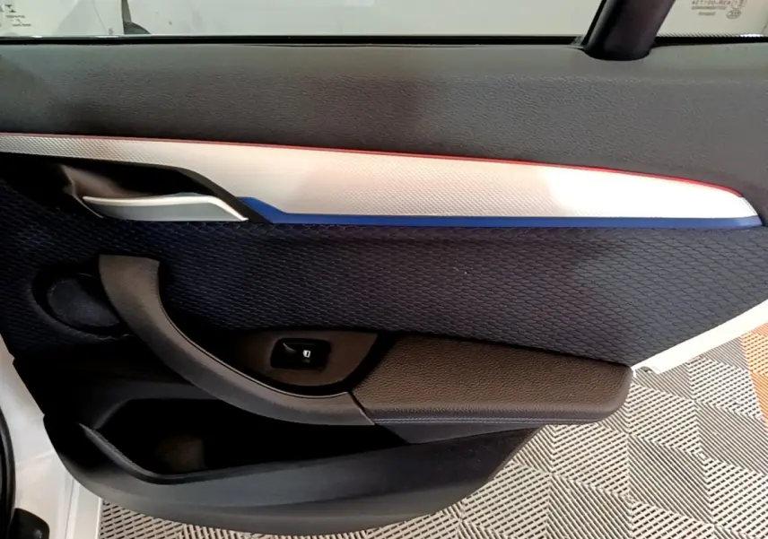 Détail de la porte côté gauche de la BMW X1 sDrive18i M Sport 2022, avec insert blanc et tissu noir texturé.