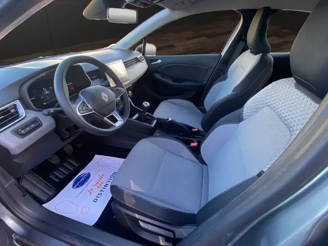 Vue intérieure côté conducteur de la Renault Clio V gris schiste, avec sellerie textile gris à motif 3D et volant textile grainé.