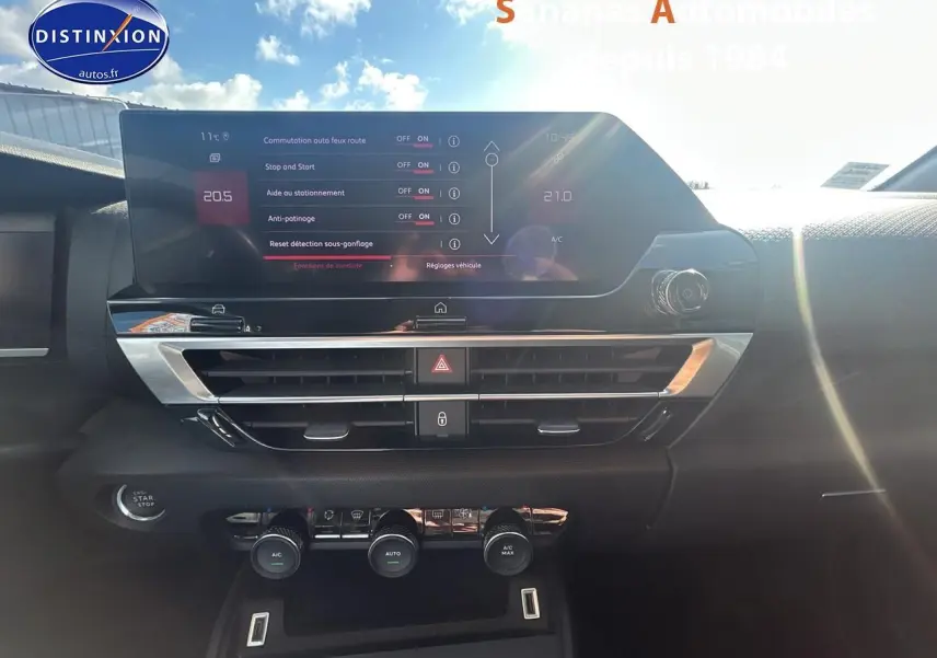 Tableau de bord de Citroën C4 2021 avec écran tactile et commandes de climatisation sous un ciel ensoleillé.