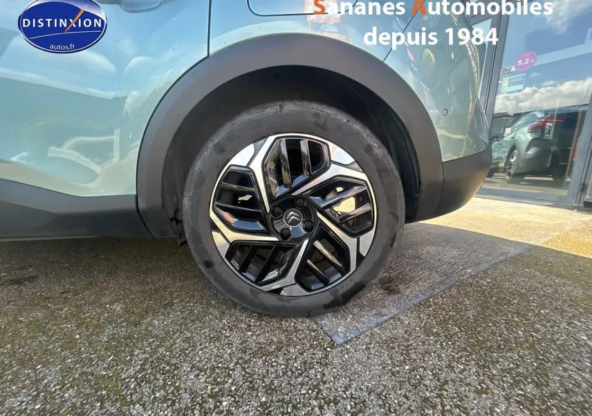 Gros plan sur la roue arrière droite d'une Citroën C4 bleu clair avec jante alliage 18 pouces au design moderne.