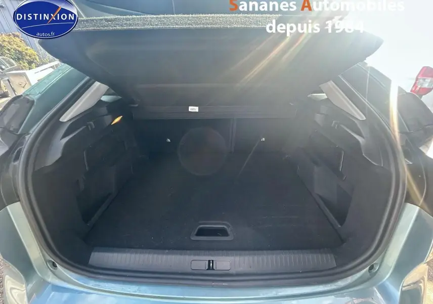 Coffre ouvert vu de l'arrière d'une Citroën C4 bleu clair 2021, montrant un espace de chargement vide et propre.
