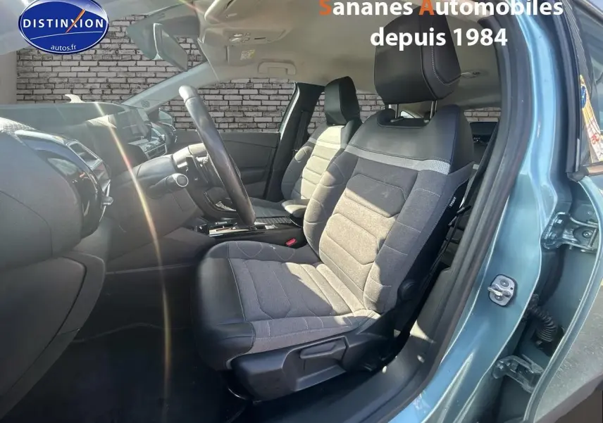 Vue intérieure côté conducteur de la Citroën C4 2021 bleu clair, sièges tissu gris et cuir noir avec tableau de bord moderne.