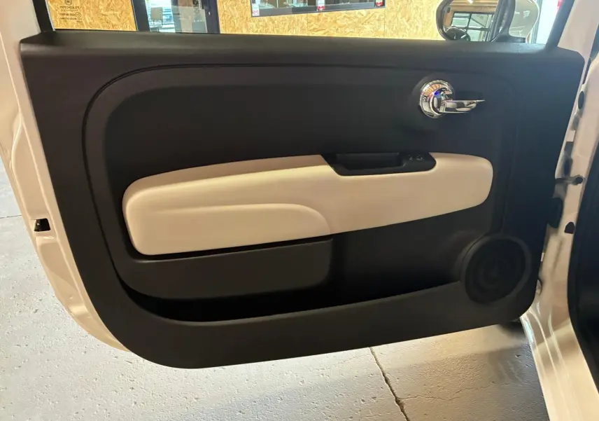 Vue intérieure de la porte avant droite d'une Fiat 500 blanc crème avec garniture noire et beige.