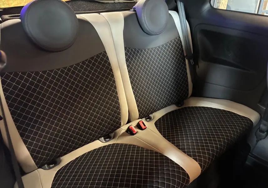 Vue intérieure des sièges arrière en tissu noir à motifs losanges avec contours crème d'une Fiat 500 DolceVita 2021.