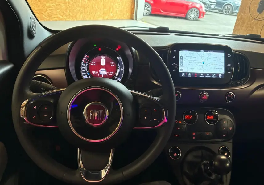 Vue intérieure centrée sur le volant FIAT et le tableau de bord avec écran tactile affichant la navigation.