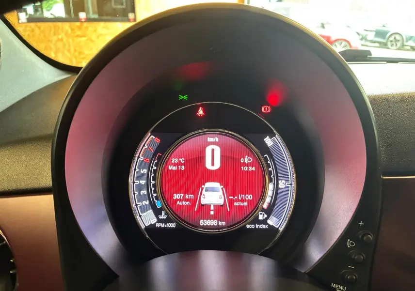 Vue rapprochée du tableau de bord numérique rouge de la Fiat 500 blanche crème, affichant la vitesse à zéro.
