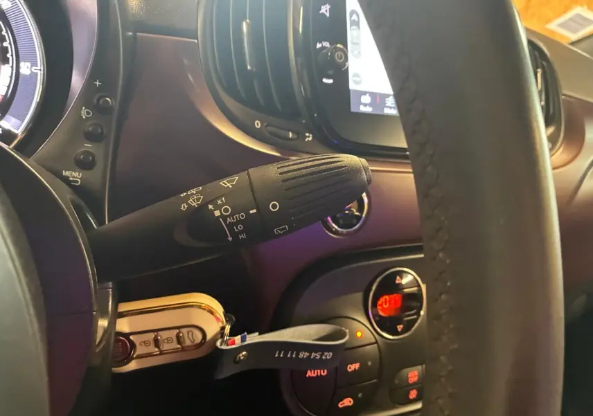Vue rapprochée du commodo d’essuie-glace à gauche du volant dans l’habitacle noir et crème d’une Fiat 500 2021.