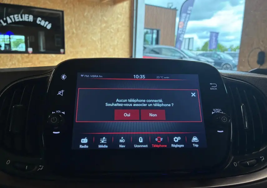 Écran tactile central de la Fiat 500 blanc crème, affichant le menu de connexion téléphone en intérieur.