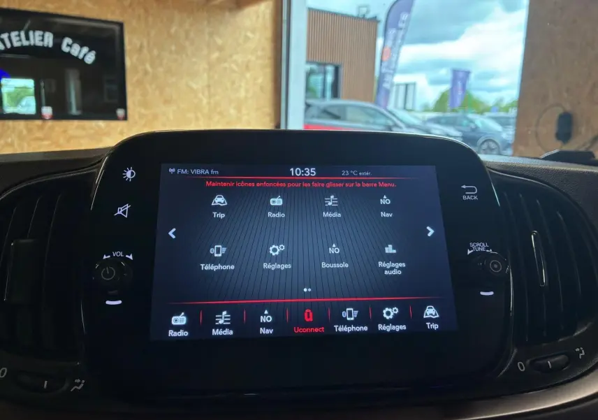 Écran tactile central allumé de la Fiat 500 blanc crème, vue intérieure frontale avec commandes autour de l'écran.