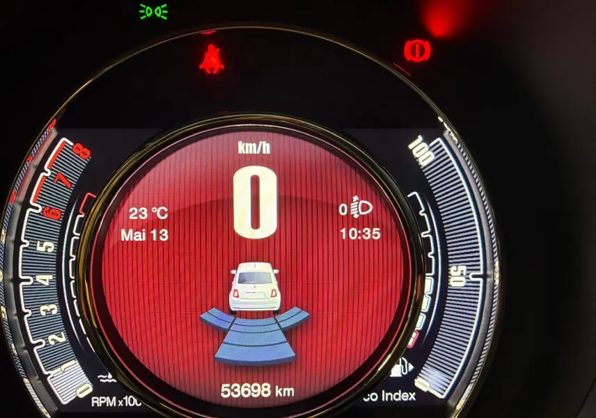 Vue rapprochée du tableau de bord numérique de la Fiat 500, affichant la vitesse à 0 km/h et l'indicateur de stationnement actif.
