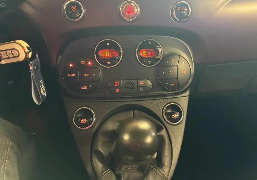 Vue rapprochée du levier de vitesses manuel et du tableau de commande de climatisation d’une Fiat 500 crème 2021.