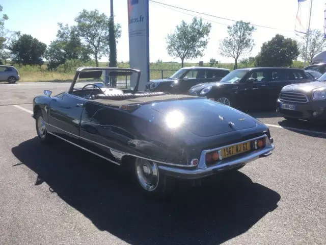 Vue 3/4 arrière d'une Citroën DS3 Cabriolet Chapron bleu marine de 1967, capote baissée, stationnée en extérieur.