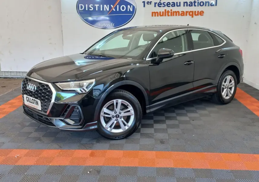 Audi Q3 Sportback noir vue 3/4 avant droit, avec calandre hexagonale et jantes argentées en intérieur showroom.