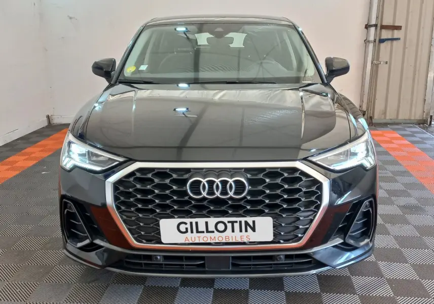 Audi Q3 Sportback noir vue de face, mettant en valeur sa calandre hexagonale et ses phares LED allumés.