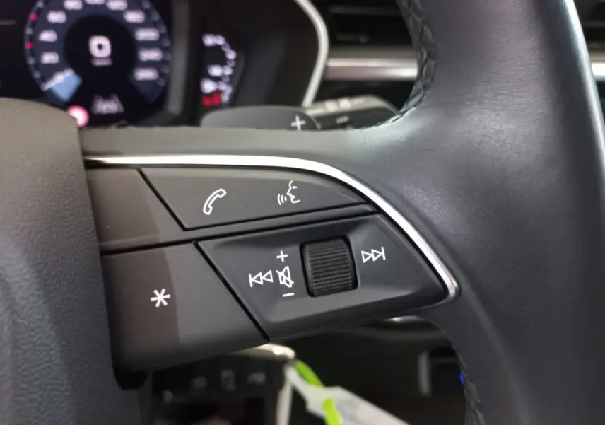 Gros plan sur les commandes vocales et audio du volant cuir noir de l'Audi Q3 Sportback 35 TDI 2020.