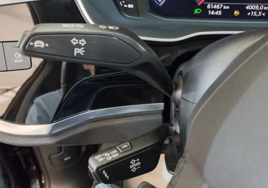 Gros plan sur les commandes au volant d'un Audi Q3 Sportback 35 TDI noir, avec affichage digital du tableau de bord en arrière-plan.