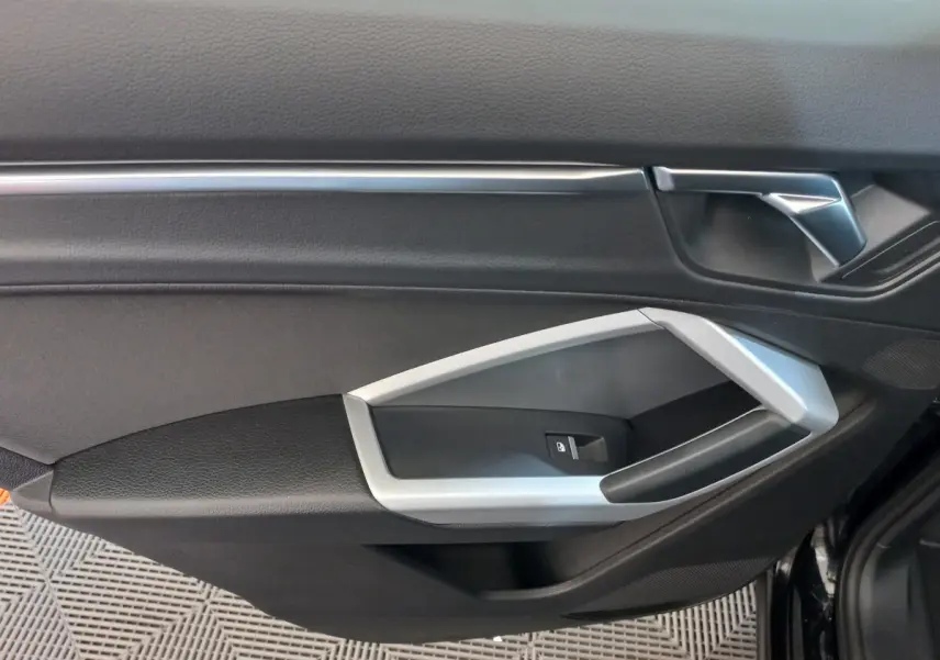 Détail de la porte côté conducteur noire de l'Audi Q3 Sportback 35 TDI 150 S tronic Business Line 2020 avec poignée argentée.