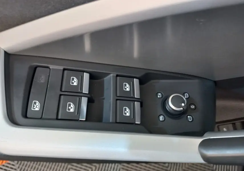 Gros plan sur les commandes de lève-vitres et réglage des rétroviseurs côté conducteur d'un Audi Q3 Sportback noir.