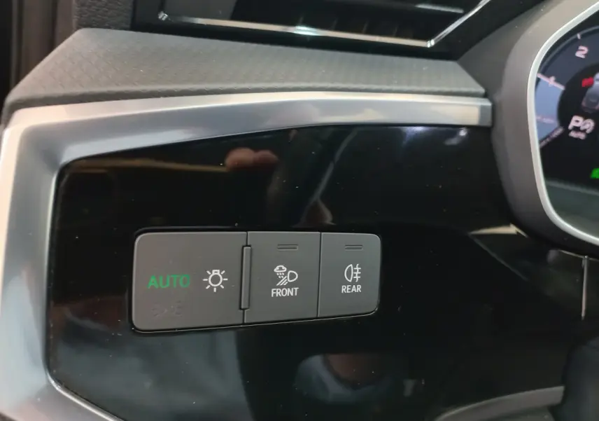 Gros plan sur les commandes d'éclairage avec mode auto, antibrouillard avant et arrière, tableau de bord noir d'Audi Q3 Sportback.