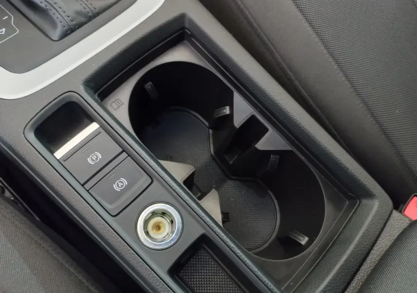 Gros plan sur la console centrale noire de l'Audi Q3 Sportback 35 TDI avec porte-gobelets et commandes électroniques.