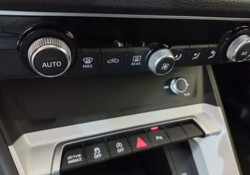 Gros plan sur la console centrale noire de l'Audi Q3 Sportback 35 TDI 150 S Tronic avec commandes climatisation et boutons multifonctions.