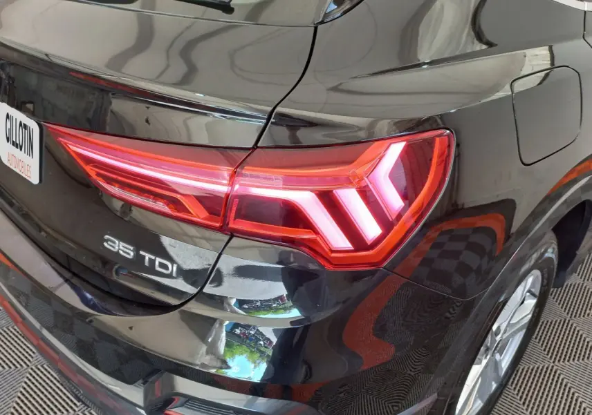 Gros plan sur l'arrière droit noir brillant de l'Audi Q3 Sportback 35 TDI avec feu LED distinctif allumé.
