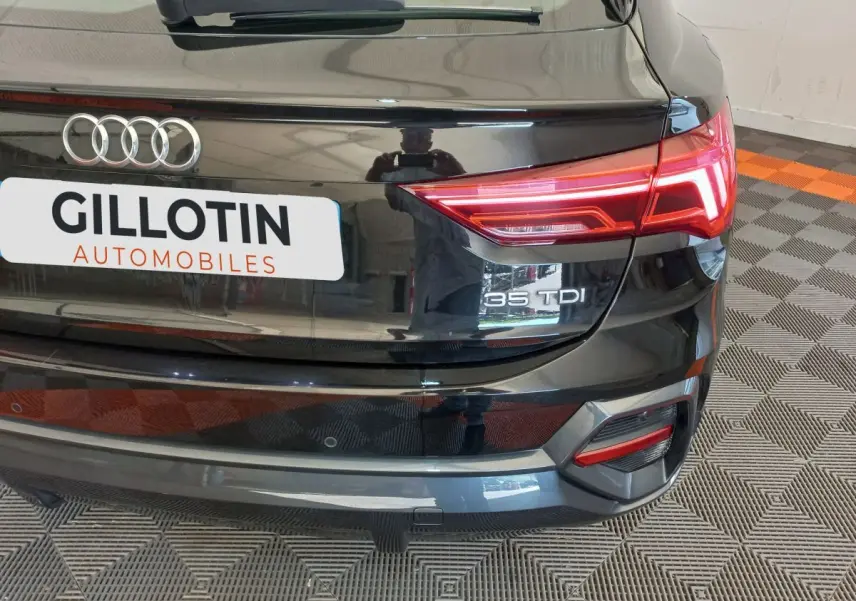 Vue arrière droite d'un Audi Q3 Sportback noir 35 TDI avec feux LED et logo distinctif sur coffre.