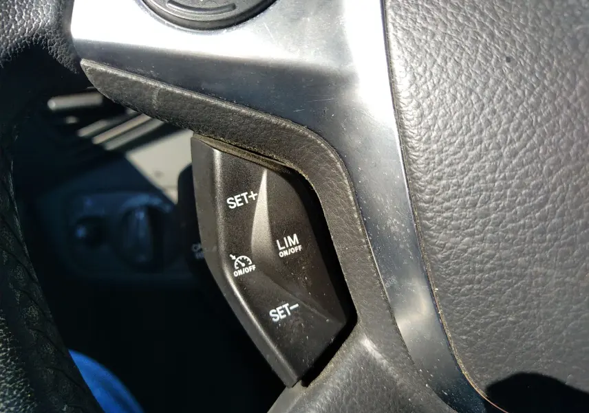 Gros plan sur les commandes de régulateur de vitesse au volant d'une Ford C-MAX blanche, version 2013.