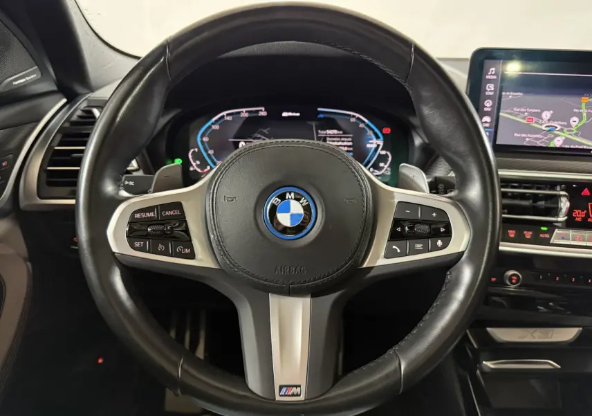 Vue rapprochée du volant cuir noir M Sport de la BMW X3 bleu avec tableau de bord digital et écran tactile.