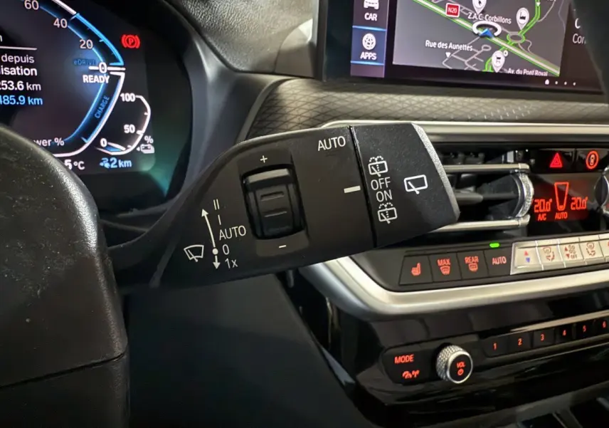Gros plan intérieur sur la commande d’essuie-glace et tableau de bord digital de la BMW X3 xDrive30e bleu 2023.